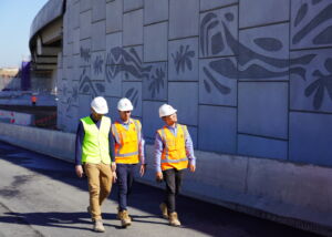 Engineers inspecting a completed reinforced earth wall (MSE wall) in Sydney, New South Wales, which has pre cast concrete facing panels with decorative elements engraved.