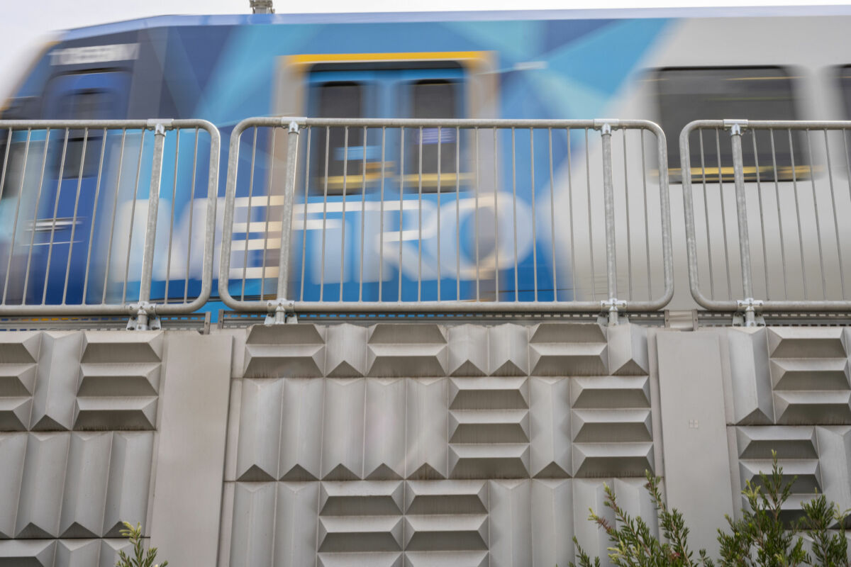 A blue Metro train in Victoria, Australia, passes through Bell Street Station, rail infrastructure supported by Geoquest MSE retaining walls and precast concrete facing panels. Close up detailed image